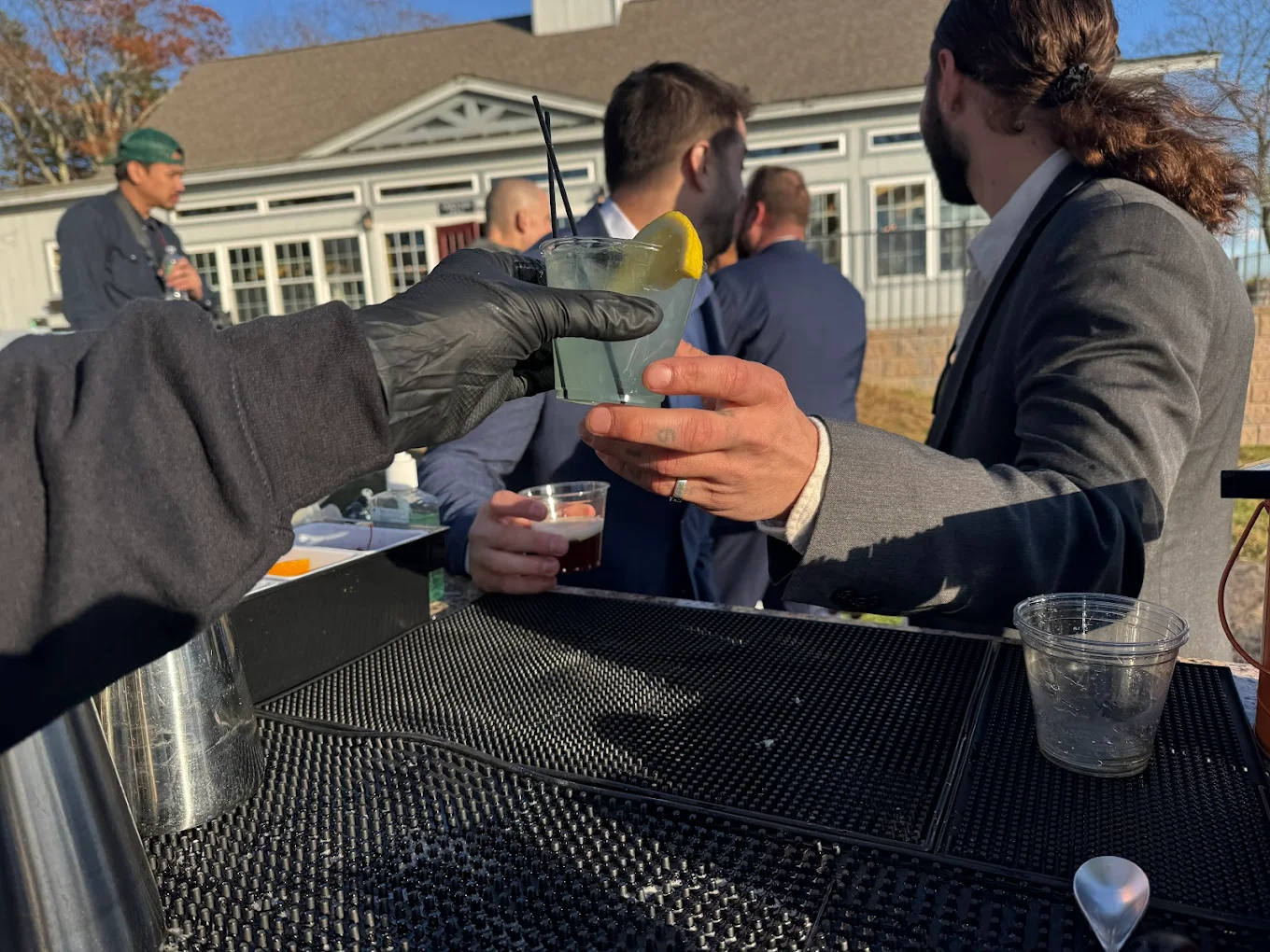 Bartender serving cocktail to guest at outdoor wedding event